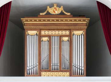 Schloss und Schlossgarten Schwetzingen - Schloss - Nordflügel, Nord-Süd-Teil - Schlosskapelle - Orgelempore - Orgel - Von Süden - Blick von unterhalb der Hofloge nach oben auf einen Teil des Orgelprospektes mit den Prospektpfeifen sowie auf das "badische" Wappen oben auf der Orgel (mit vertauschten Farben des Wappens Badens) (Orgelbauer: Andreas Ubhauser (1765-1822), Bauzeit: 1806, umfassende Restaurierung: 1980-1982, Originalteile: ca. 90 Prozent;  Windwerk: Schleifladen und elektrisches Gebläse, Register: 10, Manuale: 1 / C-f3, Pedale: 1 / C-f0; Orgelpfeifen aus Zinn, Tastatur aus Ebenholz) (aufgenommen im Juni 2023, am frühen Nachmittag)