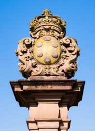Schloss und Schlossgarten Schwetzingen - Schloss - Ehrenhof / Cour d'honneur - Eingangstor, rechter / nördlicher Torpfosten - Von Osten - Blick nach oben auf das Wappen von Anna Maria Luisa de’ Medici (1667–1743), zweite Ehefrau (Heirat 1691) des Kurfürsten Johann Wilhelm (1658-1716, reg. 1690-1716); Bildhauer: Joseph Mauchert, Datierung: um 1713; ursprünglicher Aufstellungsort des Torpfostens mit dem Wappen: hinter der Brücke, um 1748 bei der Anlage des Marktplatzes vor der Brücke aufgestellt (aufgenommen im Juni 2023, am Vormittag)