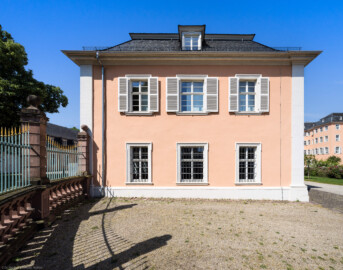 Schloss und Schlossgarten Schwetzingen - Schloss - Südflügel / Hofdamenflügel - Längsbau - Von Osten - Blick auf die Ostfassade des Längsbaus; links ein Ende des schmiedeeisernen Gitterzauns um den Ehrenhof (Südflügel: L-förmig, Länge x Breite Längsbau ca. 50 x 14 Meter, Querbau ca. 15 x 11 Meter; Architekt: Johann Adam Breunig (1660-1727); Fertigstellung: 1710, letzte Renovierung: 2009-2012) (aufgenommen im juni 2023, am späten Vormittag)