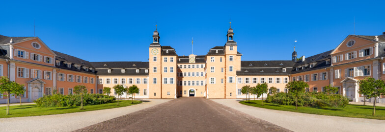 Schloss und Schlossgarten Schwetzingen - Schloss - Ostseite / Mittelbau / Süd- und Nordflügel / Ehrenhof - Von Osten - Zentraler Blick vom Ehrenhof nach Westen auf den Mittelbau mit dem Süd- und Nordturm und der Durchfahrt in den Garten sowie auf den Südflügel / Hofkavaliersflügel (links) und den Nordflügel / Hofdamenflügel (rechts) (Mittelbau und Flügel: Wiederaufbau / Erweiterung: 1698-1717; Architekten: Johann Adam Breunig, Simon Sarto) (aufgenommen im Juli 2023, am Vormittag)