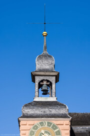 Schloss und Schlossgarten Schwetzingen - Schloss - Mittelbau - Südturm - Hofseite - Von Osten - Blick vom Ehrenhof nach oben auf den Südturm, auf das Ziffernblatt der Uhr, die Turmhaube, den Glockenstuhl mit den beiden Uhrschlagglocken, den Turmknopf und auf den Hemmerschen Fünfspitz (Glockengießer: Johann und Andreas Schneidewind / Frankfurt am Main, Gussjahr: 1724; größere / kleinere Glocke: östlich / westlich, Durchmesser 68 cm / 55 cm, Nominal/Schlagton: d'' / f'', Referenznummer (Deutscher Glockenatlas, Bd. 4, Baden, Seite 577): 1891 / 1892; Plattform unter den Glocken: nur ca. 70 x 70 cm; Aufhängung: mittels Holzjochen mit Bandeisenbeschlägen, wohl um 2010 erneuert; Uhrschlaghämmer: elektrisch betrieben und elektronisch gesteuert; Schläge: Stunden- und Viertelstundenschläge) (aufgenommen im Juli 2023, am Vormittag)