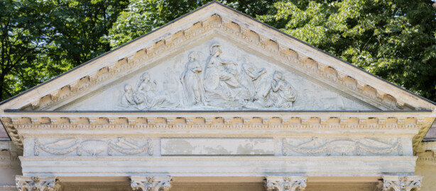 Schloss und Schlossgarten Schwetzingen - Garten - Minervatempel - Von aussen - Vorderseite - Von Nordost - Blick auf das Gebälk und das dreieckige Giebelfeld des Minervatempels; Fries mit drei Feldern, einer leeren mittleren Infschrifttafel, zwei Feldern links und rechts mit Verzierungen (Deckelvasen mit Blattgirlanden und Opferwerkzeugen); im Tympanon eine Reliefdarstellung der Göttin Minerva als Beschützerin der Gartenkunst; Relief geschaffen 1769 von Franz Conrad Linck (1730-1793) (Gesamter Bau: Breite ca. 7 Meter, Länge ca. 9 Meter, Innenraum kubisch; Rückseite zweigeschossig mit Kellerraum; Architekt: Nicolas de Pigage (1723-1796); Bauzeit: vermutlich zwischen 1767/68 und 1773) (aufgenommen im Juli 2023, um die Mittagszeit)