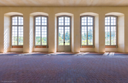 Schloss und Schlossgarten Schwetzingen - Garten - Neue Orangerie - Von innen - Östlicher Seitenflügel - Südwand - Von Norden - Blick nach Süden auf die zentrale Tür und vier Fenster des dreizehnachsigen Seitenflügels (Gesamter Bau: Länge ca. 171 Meter, Breite ca. 10-12 Meter; Bauzeit: 1761-1762; Architekt: Nicolas de Pigage; umfangreiche Instandsetzung: 1994-1999) (aufgenommen im Juli 2023, am Nachmittag)