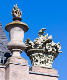 Schloss und Schlossgarten Schwetzingen - Garten - Nördlicher Zirkelbau - Östlicher Eck-Pavillon - Von Westen - Blick nach oben auf die südlichste (ganz rechts) Vase mit Flamme und den südlichen (rechten) Blumenkorb mit Blumen; Kopien, Originale der Skulpturen vermutlich gehauen von Johann Matthäus van den Branden (1716-1788) (Gesamter Bau: Länge Bogen ca. 175 Meter, Breite zwischen ca. 11 und 18 Meter, 51 Achsen, 5 Pavillons, 4 Zwischenbauten; Architekt: Alessandro Alessandro Galli da Bibiena (1686-1748), Bauleitung: zuerst Guillaume d’Hauberat (1680–1749), dann Nicolas de Pigage (1723-1796); Bauzeit: 1748-1750) (aufgenommen im August 2023, am späten Nachmittag)