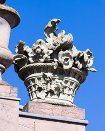 Schloss und Schlossgarten Schwetzingen - Garten - Nördlicher Zirkelbau - Östlicher Eck-Pavillon - Von Westen - Blick nach oben auf den südlichen (rechten) Blumenkorb mit Blumen; Kopie, Original der Skulptur vermutlich gehauen von Johann Matthäus van den Branden (1716-1788) (Gesamter Bau: Länge Bogen ca. 175 Meter, Breite zwischen ca. 11 und 18 Meter, 51 Achsen, 5 Pavillons, 4 Zwischenbauten; Architekt: Alessandro Alessandro Galli da Bibiena (1686-1748), Bauleitung: zuerst Guillaume d’Hauberat (1680–1749), dann Nicolas de Pigage (1723-1796); Bauzeit: 1748-1750) (aufgenommen im August 2023, am späten Nachmittag)