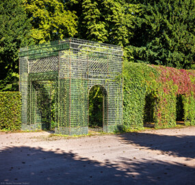 Schloss und Schlossgarten Schwetzingen - Garten - Kreisparterre - Nördlicher Laubengang, Südwestende - Von Südost - Blick nach Nordwesten auf einen Ausschnitt des nördlichen Laubengangs (Berceaux de Treillage) mit portalartigem Eingang; die Laubengänge sind mit wildem Wein und blühenden Kletterpflanzen bepflanzt (aufgenommen im August 2023, am späten Vormittag)