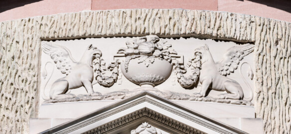 Schloss und Schlossgarten Schwetzingen - Garten - Tempel der Botanik - Von außen - Portal, Greifenrelief - Von Osten - Blick auf eine Reliefdarstellung zweier Greifen (Fabeltiere), in den Schnäbeln Girlanden aus Eichenlaub haltend, in der Mitte eine mit Früchten gefüllten Vase; Portal geschaffen von Franz Conrad Linck (1730-1793) (Tempel: Durchmesser ca. 7 Meter; Bauzeit: 1777-1780; Architekt: Nicolas de Pigage) (aufgenommen im September 2023, am späten Vormittag)