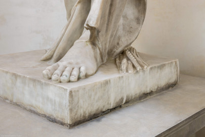 Schloss und Schlossgarten Schwetzingen - Garten - Tempel der Botanik - Von innen - Skulptur Botanik - Von Nordost - Blick auf den Fuß der Skulptur der Botanik, unter dem Gewand ein Ährenbündel; Skulptur gehauen von Francesco Carabelli (1737-1798), gekauft 1775 in Italien; ursprünglich stellte die Skulptur Ceres / Demeter dar, die Göttin des Ackerbaus und der Fruchtbarkeit, die ein Ährenbündel in ihrem Arm hielt; die Skulptur wurde umgearbeitet zur Botanik, die in ihrem linken Arm ein Bündel Papiere hielt, beschriftet mit "Caroli Linnei sistema plantarum", ein Hinweis auf die beiden bedeutsamsten Werke "Species Plantarum" und "Systema Naturae" von Carl von Linné (1707-1778); heute ist das Manuskript im linken Arm nicht mehr vorhanden (Tempel: Durchmesser ca. 7 Meter; Bauzeit: 1777-1780; Architekt: Nicolas de Pigage) (aufgenommen im September 2023, am frühen Nachmittag) Schloss und Schlossgarten Schwetzingen - Garten - Tempel der Botanik - Von innen - Skulptur Botanik - Von Nordost - Blick auf den Fuß der Skulptur der Botanik, unter dem Gewand ein Ährenbündel; Skulptur gehauen von Francesco Carabelli (1737-1798), gekauft 1775 in Italien; ursprünglich stellte die Skulptur Ceres / Demeter dar, die Göttin des Ackerbaus und der Fruchtbarkeit, die ein Ährenbündel in ihrem Arm hielt; die Skulptur wurde umgearbeitet zur Botanik, die in ihrem linken Arm ein Bündel Papiere hielt, beschriftet mit "Caroli Linnei sistema plantarum", ein Hinweis auf die beiden bedeutsamsten Werke "Species Plantarum" und "Systema Naturae" von Carl von Linné (1707-1778); heute ist das Manuskript im linken Arm nicht mehr vorhanden (Tempel: Durchmesser ca. 7 Meter; Bauzeit: 1777-1780; Architekt: Nicolas de Pigage) (aufgenommen im September 2023, am frühen Nachmittag)