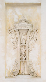 Schloss und Schlossgarten Schwetzingen - Garten - Tempel der Botanik - Von innen - Unteres großes Wandfeld, Nordostseite - Blick auf ein Stuckrelief, den Winter symbolisierend mittels zweier gekreuzter Krummstäbe mit Eichenlaub; in der Mitte ein Dreifuß mit hochaufgerichteter Schlange, oben eine Schale mit brennendem Feuer; Stuckateur Joseph Anton Pozzi (1732-1811) (Tempel: Durchmesser ca. 7 Meter; Bauzeit: 1777-1780; Architekt: Nicolas de Pigage) (aufgenommen im September 2023, am späten Vormittag) Schloss und Schlossgarten Schwetzingen - Garten - Tempel der Botanik - Von innen - Unteres großes Wandfeld, Nordostseite - Blick auf ein Stuckrelief, den Winter symbolisierend mittels zweier gekreuzter Krummstäbe mit Eichenlaub; in der Mitte ein Dreifuß mit hochaufgerichteter Schlange, oben eine Schale mit brennendem Feuer; Stuckateur Joseph Anton Pozzi (1732-1811) (Tempel: Durchmesser ca. 7 Meter; Bauzeit: 1777-1780; Architekt: Nicolas de Pigage) (aufgenommen im September 2023, am späten Vormittag)