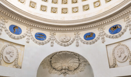 Schloss und Schlossgarten Schwetzingen - Garten - Tempel der Botanik - Von innen - Raum, Ausschnitt - Von Westen - Blick von der Skulptur der Botanik nach Osten (Richtung Eingangsür) und nach oben; unten mittig eine Muschel, umgeben von zwei gekreuzten Eichenlaubzweigen und Blüten; links (nördlich) und rechts (südlich) zwei stuckierte Reliefporträts von Naturforschern, links Plinius der Ältere (23-79), rechts Theophrastos von Eresos (371-287 v. Chr.); unterhalb der Kuppel Girlanden, dazwischen vier Tierkreiszeichen (von links: Wassermann, Fisch, Widder, Stier) und mittig ein Jahreszeiten-Medaillon (Stuckrelief mit Putto, Holz und Feuer, den Winter als Jahreszeit symbolisierend); darüber ein Kranzgesims (mit Blattstab, Zahnschnittfries, Perlstab, Eierstab, Guttae, Karnies); in der Kuppel rosettengeschmückte kleine Kassetten (Tempel: Durchmesser ca. 7 Meter; Bauzeit: 1777-1780; Architekt: Nicolas de Pigage) (aufgenommen im September 2023, am frühen Nachmittag) Schloss und Schlossgarten Schwetzingen - Garten - Tempel der Botanik - Von innen - Raum, Ausschnitt - Von Westen - Blick von der Skulptur der Botanik nach Osten (Richtung Eingangsür) und nach oben; unten mittig eine Muschel, umgeben von zwei gekreuzten Eichenlaubzweigen und Blüten; links (nördlich) und rechts (südlich) zwei stuckierte Reliefporträts von Naturforschern, links Plinius der Ältere (23-79), rechts Theophrastos von Eresos (371-287 v. Chr.); unterhalb der Kuppel Girlanden, dazwischen vier Tierkreiszeichen (von links: Wassermann, Fisch, Widder, Stier) und mittig ein Jahreszeiten-Medaillon (Stuckrelief mit Putto, Holz und Feuer, den Winter als Jahreszeit symbolisierend); darüber ein Kranzgesims (mit Blattstab, Zahnschnittfries, Perlstab, Eierstab, Guttae, Karnies); in der Kuppel rosettengeschmückte kleine Kassetten (Tempel: Durchmesser ca. 7 Meter; Bauzeit: 1777-1780; Architekt: Nicolas de Pigage) (aufgenommen im September 2023, am frühen Nachmittag)