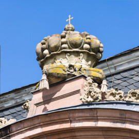 Schloss und Schlossgarten Schwetzingen - Garten - Südlicher Zirkelbau - Westlicher Eck-Pavillon - Westportal - Von Südwest - Blick nach oben auf die Krone mit Kreuz über dem Westportal; die Krone ist eine Kopie, das Original der Skulptur wurde gehauen von Johann Matthäus van den Branden (1716-1788) (Gesamter Bau: Länge Bogen ca. 175 Meter, Breite zwischen ca. 11 und 18 Meter, 51 Achsen, 5 Pavillons, 4 Zwischenbauten; Architekt: Franz Wilhelm Rabaliatti; Bauzeit: 1753-1754) (aufgenommen im September 2023, am Nachmittag)