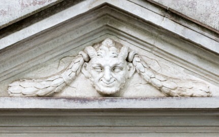Schloss und Schlossgarten Schwetzingen - Garten - Minervatempel - Von aussen - Rückseite - Portal - Von Südwest - Blick auf einen Ausschnitt des Tympanons, darin eine Maske eines Pans bzw. Fauns (Gesamter Bau: Breite ca. 7 Meter, Länge ca. 9 Meter, Innenraum kubisch; Rückseite zweigeschossig mit Kellerraum; Architekt: Nicolas de Pigage (1723-1796); Bauzeit: vermutlich zwischen 1767/68 und 1773) (aufgenommen im September 2023, am Nachmittag)