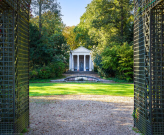 Schloss und Schlossgarten Schwetzingen - Garten - Minervatempel - Von aussen - Vorderseite - Von Nordost - Blick vom südlichen Laubengang auf den Tritonenbrunnen mit den beiden Putti und auf den Minervatempel mit (von unten nach oben) fünfstufiger Krepis, vier Säulen korinthischen Ordnung auf Plinthen, Gebälk (mit Architrav und Fries) und dreieckigem Giebelfeld mit Reliefdarstellung  (Gesamter Bau: Breite ca. 7 Meter, Länge ca. 9 Meter, Innenraum kubisch; Rückseite zweigeschossig mit Kellerraum; Architekt: Nicolas de Pigage (1723-1796); Bauzeit: vermutlich zwischen 1767/68 und 1773) (aufgenommen im September 2023, am späten Vormittag)