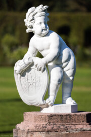 Schloss und Schlossgarten Schwetzingen - Garten - Orangeriegarten, Südöstliche Ecke - Von Südosten - Blick auf einen Putto, ein Schild mit Wappen haltend (Bildhauer: Peter van den Branden (†1720) zugeschrieben; Datierung: unbekannt) (aufgenommen im Oktober 2023, am späten Vormittag)