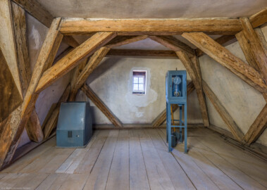 Schloss und Schlossgarten Schwetzingen - Schloss - Mittelbau - Von innen - Dachstuhl, Südseite - Dachzimmer neben/nördlich der Uhrenstube im südlichen Turm - Von Süden - Blick nach Norden in das Dachzimmer; links und rechts die beiden Teile einer mechanischen Turmuhr, Typ UT 6000, hergestellt ab 1959, der Firma Eduard Korfhage & Söhne mit Sitz in Buer bei Melle (Mittelbau: Länge Westseite ca. 45 Meter, Breite Süd-/Nordseite ca. 38 Meter; Wiederaufbau / Erweiterung: 1698-1717; Architekten: Johann Adam Breunig, Simon Sarto) (aufgenommen im Oktober 2023, am Nachmittag)