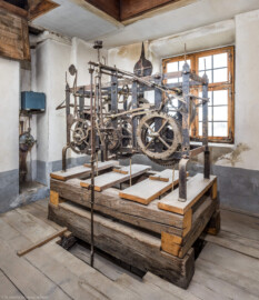 Schloss und Schlossgarten Schwetzingen - Schloss - Mittelbau - Von innen - Dachstuhl, Südseite - Uhrenstube im südlichen Turm - Von Nordwest - Blick von der Tür zur Uhrenstube auf die große alte Schlossuhr von Johann Jacob Möllinger (1695-1763) mit Viertel- und Stundenschlag, stillgelegt 1968; etliche Zahnräder und Teile der Uhr wurden demoniert, sind jedoch erhalten; die umlaufende Inschrift am oberen Rahmen der Turmuhr lautet: "AUF HOHEN CHURFÜRSTLICHEN BEFEHL WURDE DIESES WERCK VON IACOB MOELLINGER IN NEUSTATT VERFERTIGET Ao. 1763"; diese Uhr bewegte gleichzeitig vermittels einer Hebelübersetzung die Zeiger an den Uhren des Südturms, der Ost- sowie der Westfassade des Mittelbaus; die Zifferblätter der drei Uhren sind ebenso von Johann Jacob Möllinger gefertigt (Mittelbau: Länge Westseite ca. 45 Meter, Breite Süd-/Nordseite ca. 38 Meter; Wiederaufbau / Erweiterung: 1698-1717; Architekten: Johann Adam Breunig, Simon Sarto) (aufgenommen im November 2023, am frühen Nachmittag) Schloss und Schlossgarten Schwetzingen - Schloss - Mittelbau - Von innen - Dachstuhl, Südseite - Uhrenstube im südlichen Turm - Von Nordwest - Blick von der Tür zur Uhrenstube auf die große alte Schlossuhr von Johann Jacob Möllinger (1695-1763) mit Viertel- und Stundenschlag, stillgelegt 1968; etliche Zahnräder und Teile der Uhr wurden demoniert, sind jedoch erhalten; die umlaufende Inschrift am oberen Rahmen der Turmuhr lautet: "AUF HOHEN CHURFÜRSTLICHEN BEFEHL WURDE DIESES WERCK VON IACOB MOELLINGER IN NEUSTATT VERFERTIGET Ao. 1763"; diese Uhr bewegte gleichzeitig vermittels einer Hebelübersetzung die Zeiger an den Uhren des Südturms, der Ost- sowie der Westfassade des Mittelbaus; die Zifferblätter der drei Uhren sind ebenso von Johann Jacob Möllinger gefertigt (Mittelbau: Länge Westseite ca. 45 Meter, Breite Süd-/Nordseite ca. 38 Meter; Wiederaufbau / Erweiterung: 1698-1717; Architekten: Johann Adam Breunig, Simon Sarto) (aufgenommen im November 2023, am frühen Nachmittag)
