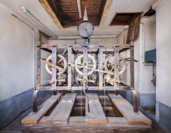 Schloss und Schlossgarten Schwetzingen - Schloss - Mittelbau - Von innen - Dachstuhl, Südseite - Uhrenstube im südlichen Turm - Von Süden - Blick vom Fenster auf die Frontseite der großen alten Schlossuhr von Johann Jacob Möllinger (1695-1763) mit Viertel- und Stundenschlag, stillgelegt 1968; etliche Zahnräder und Teile der Uhr wurden demoniert, sind jedoch erhalten; die umlaufende Inschrift am oberen Rahmen der Turmuhr lautet: "AUF HOHEN CHURFÜRSTLICHEN BEFEHL WURDE DIESES WERCK VON IACOB MOELLINGER IN NEUSTATT VERFERTIGET Ao. 1763"; diese Uhr bewegte gleichzeitig vermittels einer Hebelübersetzung die Zeiger an den Uhren des Südturms, der Ost- sowie der Westfassade des Mittelbaus; die Zifferblätter der drei Uhren sind ebenso von Johann Jacob Möllinger gefertigt (Mittelbau: Länge Westseite ca. 45 Meter, Breite Süd-/Nordseite ca. 38 Meter; Wiederaufbau / Erweiterung: 1698-1717; Architekten: Johann Adam Breunig, Simon Sarto) (aufgenommen im November 2023, am frühen Nachmittag) Schloss und Schlossgarten Schwetzingen - Schloss - Mittelbau - Von innen - Dachstuhl, Südseite - Uhrenstube im südlichen Turm - Von Süden - Blick vom Fenster auf die Frontseite der großen alten Schlossuhr von Johann Jacob Möllinger (1695-1763) mit Viertel- und Stundenschlag, stillgelegt 1968; etliche Zahnräder und Teile der Uhr wurden demoniert, sind jedoch erhalten; die umlaufende Inschrift am oberen Rahmen der Turmuhr lautet: "AUF HOHEN CHURFÜRSTLICHEN BEFEHL WURDE DIESES WERCK VON IACOB MOELLINGER IN NEUSTATT VERFERTIGET Ao. 1763"; diese Uhr bewegte gleichzeitig vermittels einer Hebelübersetzung die Zeiger an den Uhren des Südturms, der Ost- sowie der Westfassade des Mittelbaus; die Zifferblätter der drei Uhren sind ebenso von Johann Jacob Möllinger gefertigt (Mittelbau: Länge Westseite ca. 45 Meter, Breite Süd-/Nordseite ca. 38 Meter; Wiederaufbau / Erweiterung: 1698-1717; Architekten: Johann Adam Breunig, Simon Sarto) (aufgenommen im November 2023, am frühen Nachmittag)