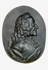 Schloss und Schlossgarten Schwetzingen - Schloss - Mittelbau - Von innen - 1. Obergeschoss - Appartment des Kurfürsten - Konferenzzimmer - Südwand, links der Mitte - Portrait-Relief von Voltaire (1694-1778) (Bildhauer: Franz Conrad Linck (1730-1793), Datierung: 1777; Material: Gips, schwarz gefärbt) (aufgenommen im Januar 2024, am  Nachmittag)