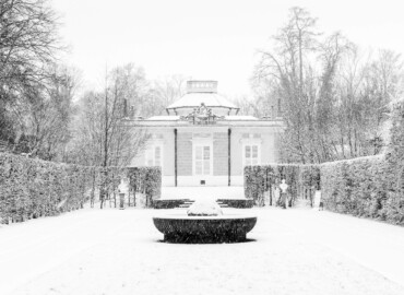 Schloss und Schlossgarten Schwetzingen - Garten - Badhaus - Von aussen - Ostseite - Von Osten - Blick auf die Ostseite des Badhauses bei Schneefall; vorne die Wasserglocke (den Brunnen), links und rechts zwei Büsten (Gesamter Bau: Länge x Breite ca. 18 x 14 Meter, Höhe ca. 10 Meter; Architekt: Nicolas de Pigage (1723-1796); Bauzeit: 1768-1772; Gesamtinstandsetzung innen und außen: 1999-2006) (aufgenommen im Januar 2024, um die Mittagszeit)