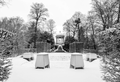Schloss und Schlossgarten Schwetzingen - Garten - Naturtheater - Von Osten - Blick vom östlichen Eingang zum Naturtheater auf die Anlage bei Schneefall; oben der Tempel des Apoll, darunter der Najadenbrunnen und die Kaskaden mit beidseitigen Treppen, davor die leicht erhöhte Bühne mit durch Hecken angedeutete Proszenien, vorne drei Treppen (geschmückt mit Sphingen, verdeckt durch Wintereinhausungen) zum etwas tiefer gelegenen Zuschauerraum (aufgenommen im Januar 2024, am frühen Nachmittag)