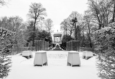 Schloss und Schlossgarten Schwetzingen - Garten - Naturtheater - Von Osten - Blick vom östlichen Eingang zum Naturtheater auf die Anlage bei Schneefall; oben der Tempel des Apoll, darunter der Najadenbrunnen und die Kaskaden mit beidseitigen Treppen, davor die leicht erhöhte Bühne mit durch Hecken angedeutete Proszenien, vorne drei Treppen (geschmückt mit Sphingen, verdeckt durch Wintereinhausungen) zum etwas tiefer gelegenen Zuschauerraum (aufgenommen im Januar 2024, am frühen Nachmittag) Schloss und Schlossgarten Schwetzingen - Garten - Naturtheater - Von Osten - Blick vom östlichen Eingang zum Naturtheater auf die Anlage bei Schneefall; oben der Tempel des Apoll, darunter der Najadenbrunnen und die Kaskaden mit beidseitigen Treppen, davor die leicht erhöhte Bühne mit durch Hecken angedeutete Proszenien, vorne drei Treppen (geschmückt mit Sphingen, verdeckt durch Wintereinhausungen) zum etwas tiefer gelegenen Zuschauerraum (aufgenommen im Januar 2024, am frühen Nachmittag)