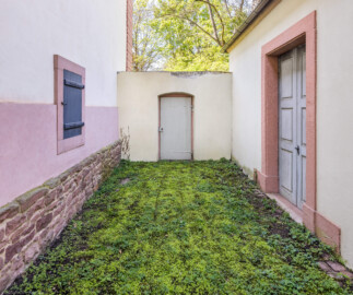 Schloss und Schlossgarten Schwetzingen - Garten - Pfauenhaus - Von außen - Von Osten - Blick nach Westen auf die Abschlusswand mit Tür, links die Nordseite des westlichen Eckpavillons der Neuen Orangerie, rechts die Südseite des Pfauenhauses mit Tür (Bau: Grundfläche ca. 9 x 9 Meter; Bauzeit: 1762-1764; Architekt: Nicolas de Pigage) (aufgenommen im April 2024, am frühen Nachmittag) Schloss und Schlossgarten Schwetzingen - Garten - Pfauenhaus - Von außen - Von Osten - Blick nach Westen auf die Abschlusswand mit Tür, links die Nordseite des westlichen Eckpavillons der Neuen Orangerie, rechts die Südseite des Pfauenhauses mit Tür (Bau: Grundfläche ca. 9 x 9 Meter; Bauzeit: 1762-1764; Architekt: Nicolas de Pigage) (aufgenommen im April 2024, am frühen Nachmittag)