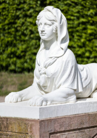 Schloss und Schlossgarten Schwetzingen - Garten - Naturtheater - Parterre - Ostseite, nördliche Sphynx - Von Südwest - Blick auf eine der sechs Sphyngen (als Allegorien der Musik, des Tanzes, der Komödie, der Tragödie und als Wächterinnen) neben der Treppe zum Zuschauerraum, auf einem Postament liegend (Bildhauer: Peter Anton von Verschaffelt (1710-1793), Datierung: 1766-1773; Material: gelber Sandstein, weiß gefasst, Höhe ca. 100 cm, Postament 160 x 63 cm) (aufgenommen im April 2024, am Nachmittag) Schloss und Schlossgarten Schwetzingen - Garten - Naturtheater - Parterre - Ostseite, nördliche Sphynx - Von Südwest - Blick auf eine der sechs Sphyngen (als Allegorien der Musik, des Tanzes, der Komödie, der Tragödie und als Wächterinnen) neben der Treppe zum Zuschauerraum, auf einem Postament liegend (Bildhauer: Peter Anton von Verschaffelt (1710-1793), Datierung: 1766-1773; Material: gelber Sandstein, weiß gefasst, Höhe ca. 100 cm, Postament 160 x 63 cm) (aufgenommen im April 2024, am Nachmittag)
