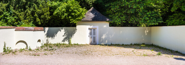 Schloss und Schlossgarten Schwetzingen - Garten - Fasanenhof - Von Süden - Blick vom südlichen Fasanenbruthaus nach Norden auf den Hof und auf das gegenüberliegende Fasanenbruthaus; der Fasanenhof war ehemals dreigeteilt: in der Mitte ein Weg zum Apollokanal (nach links) und zum Arboretum (nach rechts), davor und dahinter durch Gitter und durch Netze nach oben geschlossene Gehege; an der kleinen Aussichtsterrasse mit den beiden Bögen unten (im Bild links) befinden sich heute noch oben an der Umfassung aus rotem Sandstein einige der Metallhaken, an denen ehemals Netze über die beiden Gehege aufgespannt wurden; gezüchtet wurden Fasane zum Aussetzen bei Jagden (Hof: Länge x Breite (ohne Bruthäuser) ca. 18 Meter x 14 Meter; Bauzeit: zwischen 1763 und 1767 (gleichzeitig mit der ehemaligen Menagerie); Architekt: Nicolas de Pigage) (aufgenommen im Mai 2024, am späten Vormittag) Schloss und Schlossgarten Schwetzingen - Garten - Fasanenhof - Von Süden - Blick vom südlichen Fasanenbruthaus nach Norden auf den Hof und auf das gegenüberliegende Fasanenbruthaus; der Fasanenhof war ehemals dreigeteilt: in der Mitte ein Weg zum Apollokanal (nach links) und zum Arboretum (nach rechts), davor und dahinter durch Gitter und durch Netze nach oben geschlossene Gehege; an der kleinen Aussichtsterrasse mit den beiden Bögen unten (im Bild links) befinden sich heute noch oben an der Umfassung aus rotem Sandstein einige der Metallhaken, an denen ehemals Netze über die beiden Gehege aufgespannt wurden; gezüchtet wurden Fasane zum Aussetzen bei Jagden (Hof: Länge x Breite (ohne Bruthäuser) ca. 18 Meter x 14 Meter; Bauzeit: zwischen 1763 und 1767 (gleichzeitig mit der ehemaligen Menagerie); Architekt: Nicolas de Pigage) (aufgenommen im Mai 2024, am späten Vormittag)