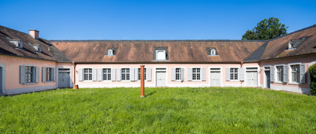 Schloss und Schlossgarten Schwetzingen - Garten - Invalidenkaserne (ehemaliges Baumagazin) - Westflügel / Innenhof - Von Osten - Blick nach Westen auf die Ostfassade des Westflügels (genutzt als Ausstellungsraum von xylon) sowie in den abgeschlossenen Innenhof; links ein Teil des Südflügels (genutzt von xylon), rechts ein Teil des Nordflügels (genutzt als Werkstattsraum von xylon) (Vierflügelanlage: Länge x Breite: ca. 60 x 50 Meter; Westflügel: ca. 50 x 10 Meter; Bauzeit: um 1774; Architekt des Baummagazins: Nicolas de Pigage; Umbau zur Kaserne: Ingenieur-Oberst von Pfister) (aufgenommen im Juni 2024, am Vormittag) Schloss und Schlossgarten Schwetzingen - Garten - Invalidenkaserne (ehemaliges Baumagazin) - Westflügel / Innenhof - Von Osten - Blick nach Westen auf die Ostfassade des Westflügels (genutzt als Ausstellungsraum von xylon) sowie in den abgeschlossenen Innenhof; links ein Teil des Südflügels (genutzt von xylon), rechts ein Teil des Nordflügels (genutzt als Werkstattsraum von xylon) (Vierflügelanlage: Länge x Breite: ca. 60 x 50 Meter; Westflügel: ca. 50 x 10 Meter; Bauzeit: um 1774; Architekt des Baummagazins: Nicolas de Pigage; Umbau zur Kaserne: Ingenieur-Oberst von Pfister) (aufgenommen im Juni 2024, am Vormittag)