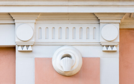 Schloss und Schlossgarten Schwetzingen - Garten - Invalidenkaserne (ehemaliges Baumagazin) - Nordflügel, Westseite - Fontainenportal - Von Norden - Blick auf Verzierungen an den beiden äußeren Wandfeldern unterhalb des Giebels; vier quadratische Flächen, darin runde Scheiben, darunter je drei Guttae; in der Mitte zwei in die Horizontale gekippte und abgeschnittene wasserspendenden Vasen (Vierflügelanlage: Länge x Breite: ca. 60 x 50 Meter; Nordflügel: ca. 30 x 10 Meter; Bauzeit: um 1774; Architekt des Baummagazins: Nicolas de Pigage; Umbau zur Kaserne: Ingenieur-Oberst von Pfister) (aufgenommen im Juli 2024, am frühen Vormittag)
