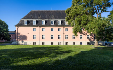 Schloss und Schlossgarten Schwetzingen - Garten - Schlosstheater - Von Norden - Blick vom Gesandtenhausgarten nach Süden auf die Nordfassade des Theaterbaus; die rechten 7 Fenster der Fassade gehören zur Seitenbühne; hinter der Wand links davon befindet sich das Foyer und Treppenhaus, dahinter der Zuschauerrraum; ganz links zwei Schnurbäume und ganz rechts ein Schnurbaum (Sophora japonica, links Baum-Nr. 72 und 73, rechts Baum-Nr. 85) (Gesamter Bau: Länge x Breite: ca. 62 x 35 Meter; Architekt: Nicolas de Pigage (1723-1796); Bauzeit: 1752-1753, Erweiterung 1762, Sanierung: 1937, Renovierung: 1952, Generalsanierung / Umbau 1971-1974, Restaurierung: 1999-2005) (aufgenommen im Juli 2024, am frühen Vormittag) Schloss und Schlossgarten Schwetzingen - Garten - Schlosstheater - Von Norden - Blick vom Gesandtenhausgarten nach Süden auf die Nordfassade des Theaterbaus; die rechten 7 Fenster der Fassade gehören zur Seitenbühne; hinter der Wand links davon befindet sich das Foyer und Treppenhaus, dahinter der Zuschauerrraum; ganz links zwei Schnurbäume und ganz rechts ein Schnurbaum (Sophora japonica, links Baum-Nr. 72 und 73, rechts Baum-Nr. 85) (Gesamter Bau: Länge x Breite: ca. 62 x 35 Meter; Architekt: Nicolas de Pigage (1723-1796); Bauzeit: 1752-1753, Erweiterung 1762, Sanierung: 1937, Renovierung: 1952, Generalsanierung / Umbau 1971-1974, Restaurierung: 1999-2005) (aufgenommen im Juli 2024, am frühen Vormittag)