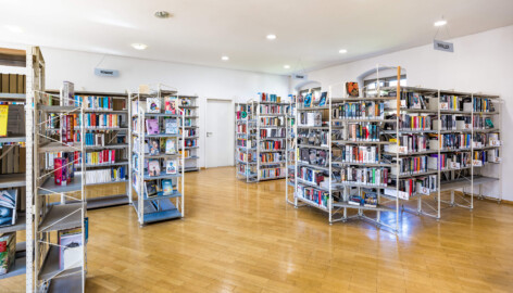 Schloss und Schlossgarten Schwetzingen - Garten - Invalidenkaserne (ehemaliges Baumagazin) / Stadtbibliothek  - Südflügel - Von innen - Erdgeschoss - Von Osten - Blick nach Westen in den Bibliotheksraum des Südflügels (Vierflügelanlage: Länge x Breite: ca. 60 x 50 Meter; Ostflügel: ca. 60 x 10 Meter; Bauzeit: um 1774; Architekt des Baummagazins: Nicolas de Pigage; Umbau zur Kaserne: Ingenieur-Oberst von Pfister) (aufgenommen im Juli 2024, am frühen Nachmittag)