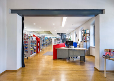 Schloss und Schlossgarten Schwetzingen - Garten - Invalidenkaserne (ehemaliges Baumagazin) / Stadtbibliothek  - Ostflügel - Von innen - Erdgeschoss - Von Südost - Blick vom Eingangsbereich nach Nordwest in den Bibliotheksraum (Vierflügelanlage: Länge x Breite: ca. 60 x 50 Meter; Ostflügel: ca. 60 x 10 Meter; Bauzeit: um 1774; Architekt des Baummagazins: Nicolas de Pigage; Umbau zur Kaserne: Ingenieur-Oberst von Pfister) (aufgenommen im Juli 2024, am frühen Nachmittag)