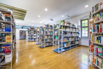 Schloss und Schlossgarten Schwetzingen - Garten - Invalidenkaserne (ehemaliges Baumagazin) / Stadtbibliothek  - Ostflügel - Von innen - Erdgeschoss - Von Südost - Blick nach Nordwest in den Bibliotheksraum (Vierflügelanlage: Länge x Breite: ca. 60 x 50 Meter; Ostflügel: ca. 60 x 10 Meter; Bauzeit: um 1774; Architekt des Baummagazins: Nicolas de Pigage; Umbau zur Kaserne: Ingenieur-Oberst von Pfister) (aufgenommen im Juli 2024, am frühen Nachmittag)