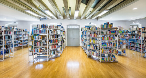 Schloss und Schlossgarten Schwetzingen - Garten - Invalidenkaserne (ehemaliges Baumagazin) / Stadtbibliothek  - Ostflügel - Von innen - Erdgeschoss - Von Nordost - Blick nach Südwest in den Bibliotheksraum und auf die Tür zum Innenhof (Vierflügelanlage: Länge x Breite: ca. 60 x 50 Meter; Ostflügel: ca. 60 x 10 Meter; Bauzeit: um 1774; Architekt des Baummagazins: Nicolas de Pigage; Umbau zur Kaserne: Ingenieur-Oberst von Pfister) (aufgenommen im Juli 2024, am frühen Nachmittag)