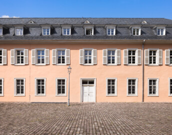 Schloss und Schlossgarten Schwetzingen - Schloss - Südflügel / Hofdamenflügel - Längsbau - Von Süden - Blick auf die Südfassade und das südliche Hauptportal des Längsbaus (Südflügel: L-förmig, Länge x Breite Längsbau ca. 50 x 14 Meter, Querbau ca. 15 x 11 Meter; Architekt: Johann Adam Breunig (1660-1727); Fertigstellung: 1710, letzte Renovierung: 2009-2012) (aufgenommen im August 2024, am Nachmittag)