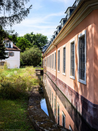Schloss und Schlossgarten Schwetzingen - Schloss - Küchenflügel / Küchenbau - Längsbau, Südseite - Von Südost - Blick vom östlichen Ende des Längsbaus nach Westen auf die Südfassade des Längsbaus, auf den Leimbach-Kanal, die kleine Brücke zum südlichen Eingang zum Längsbau sowie auf das Studentenhaus (links) (Küchenflügel: L-förmig, Länge x Breite Längsbau ca. 75 x 13 Meter, Querbau ca. 25 x 11 Meter; Architekt: Nicolas de Pigage (1723-1796); Fertigstellung: 1761, letzte Renovierung: 2009-2012) (aufgenommen im August 2024, am frühen Nachmittag) Schloss und Schlossgarten Schwetzingen - Schloss - Küchenflügel / Küchenbau - Längsbau, Südseite - Von Südost - Blick vom östlichen Ende des Längsbaus nach Westen auf die Südfassade des Längsbaus, auf den Leimbach-Kanal, die kleine Brücke zum südlichen Eingang zum Längsbau sowie auf das Studentenhaus (links) (Küchenflügel: L-förmig, Länge x Breite Längsbau ca. 75 x 13 Meter, Querbau ca. 25 x 11 Meter; Architekt: Nicolas de Pigage (1723-1796); Fertigstellung: 1761, letzte Renovierung: 2009-2012) (aufgenommen im August 2024, am frühen Nachmittag)