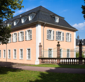 Schloss und Schlossgarten Schwetzingen - Schloss - Südflügel / Hofdamenflügel - Längsbau - Von Südost - Blick vom Innenhof auf einen Teil der Südfassade (links der Mitte) sowie auf die Ostfassade des Längsbaus (rechts der Mitte); rechts ein Ende des schmiedeeisernen Gitterzauns um den Ehrenhof; rechts im Hindergrund der Nordflügel (Südflügel: L-förmig, Länge x Breite Längsbau ca. 50 x 14 Meter, Querbau ca. 15 x 11 Meter; Architekt: Johann Adam Breunig (1660-1727); Fertigstellung: 1710, letzte Renovierung: 2009-2012) (aufgenommen im August 2024, am späten Vormittag)