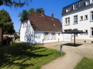 Schloss und Schlossgarten Schwetzingen - Schloss - Hochschule für Rechtspflege & Justizakademie - Dozentenhaus / Verwaltungsbau - Von Südwest - Blick auf die Rückseiten des Dozentenhauses (Mitte) sowie des Verwaltungsgebäudes (rechts); ganz links die Ostseite des Küchenbaus, daneben der Leimbachkanal, links im Hintergrund das südliche Wachthaus Dozentenhaus: Länge x Breite ca. 25 x 10 Meter; letzte Renovierung: 2009-2012) (aufgenommen im August 2024, am Nachmittag)