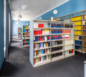 Schloss und Schlossgarten Schwetzingen - Schloss - Verbindungsbau Küchenbau-Zirkelbau / Alte Galerie - Von Innen - Erdgeschoss - Bibliothek und Leseraum - Von Osten - Blick von der Tür zur Bibliothek in den Raum mit den Präsenzbeständen und einigen Arbeitsplätzen (Verbindungsbau: Länge ca. 45 Meter, Breite ca. 8 Meter; Bauzeit: wohl um 1724; Architekt: unklar, evtl. Alessandro Galli da Bibiena (1686-1748) oder Johann Adam Breunig (1660-1727)) (aufgenommen im August 2024, am Nachmittag)