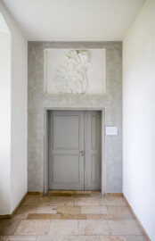 Schloss und Schlossgarten Schwetzingen - Schloss - Küchenflügel / Küchenbau - Längsbau - Von innen - Erdgeschoss - Gang / Hörsaal 6 - Von Westen - Blick auf den Eingangsbereich zum Hörsaal 6; Wandfläche um Tür ausgeführt in Stuccolustro (glänzender Stuck, eine historische Spachteltechnik); oben im vertieftem Wandfeld ein Stuckrelief (Küchenflügel: L-förmig, Länge x Breite Längsbau ca. 75 x 13 Meter, Querbau ca. 25 x 11 Meter; Architekt: Nicolas de Pigage (1723-1796); Fertigstellung: 1761, letzte Renovierung: 2009-2012) (aufgenommen im August 2024, um die Mittagszeit) Schloss und Schlossgarten Schwetzingen - Schloss - Küchenflügel / Küchenbau - Längsbau - Von innen - Erdgeschoss - Gang / Hörsaal 6 - Von Westen - Blick auf den Eingangsbereich zum Hörsaal 6; Wandfläche um Tür ausgeführt in Stuccolustro (glänzender Stuck, eine historische Spachteltechnik); oben im vertieftem Wandfeld ein Stuckrelief (Küchenflügel: L-förmig, Länge x Breite Längsbau ca. 75 x 13 Meter, Querbau ca. 25 x 11 Meter; Architekt: Nicolas de Pigage (1723-1796); Fertigstellung: 1761, letzte Renovierung: 2009-2012) (aufgenommen im August 2024, um die Mittagszeit)