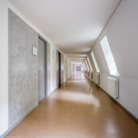 Schloss und Schlossgarten Schwetzingen - Schloss - Küchenflügel / Küchenbau -  Längsbau - Von innen - Dachgeschoss - Gang  - Von Osten - Blick vom Hörsaal 10 nach Westen in den ca. 60 Meter langen Gang; vorne links die Tür zum Hörsaal 9; Wandfläche um Türen ausgeführt in Stuccolustro (glänzender Stuck, eine historische Spachteltechnik) (Küchenflügel: L-förmig, Länge x Breite Längsbau ca. 75 x 13 Meter, Querbau ca. 25 x 11 Meter; Architekt: Nicolas de Pigage (1723-1796); Fertigstellung: 1761, letzte Renovierung: 2009-2012) (aufgenommen im August 2024, am Nachmittag)
