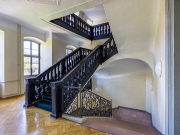 Schloss und Schlossgarten Schwetzingen - Garten - Gesandtenhaus (ehemaliges Prinzenhaus) / Amtsgericht - Von Innen - Treppenhaus / Obergeschoss - Von Nordwest - Links: Blick auf die barocke Holztreppe vom Obergeschoss ins Dachgeschoss; rechts: die Steintreppe ins Erdgeschoss mit dem barocken schmiedeeisernen Treppengeländer und den Initialen von Carl Philipp von der Pfalz (1661-1742, reg. 1716-1742) (aufgenommen im August 2024, am späten Nachmittag)