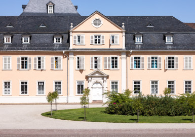 Schloss und Schlossgarten Schwetzingen - Schloss - Nordflügel / Hofkavaliersflügel - Längsbau - Von Süden - Blick vom Obergeschoss des Südflügels nach Norden auf den Ehrenhof und auf die Südfassade des Nordflügels; links der Mitte im Hintergrund das Dach des Oberen Wasserwerks (Nordflügel: L-förmig, Länge x Breite Längsbau ca. 50 x 14 Meter, Querbau ca. 15 x 12 Meter; Architekt: Johann Adam Breunig (1660-1727); Fertigstellung: 1710) (aufgenommen im August 2024, am frühen Nachmittag) Schloss und Schlossgarten Schwetzingen - Schloss - Nordflügel / Hofkavaliersflügel - Längsbau - Von Süden - Blick vom Obergeschoss des Südflügels nach Norden auf den Ehrenhof und auf die Südfassade des Nordflügels; links der Mitte im Hintergrund das Dach des Oberen Wasserwerks (Nordflügel: L-förmig, Länge x Breite Längsbau ca. 50 x 14 Meter, Querbau ca. 15 x 12 Meter; Architekt: Johann Adam Breunig (1660-1727); Fertigstellung: 1710) (aufgenommen im August 2024, am frühen Nachmittag)