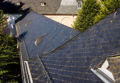 Schloss und Schlossgarten Schwetzingen - Schloss - Verbindungsbau Küchenbau-Zirkelbau / Alte Galerie - Von Oben - Blick vom ersten Fenster südlich des Verbindungsbaus im Dachgeschoss des Querbaus des Küchenflügels nach Westen auf das Dach des Verbindungsbaus; im Hintergrund der südliche Zirkelbau (Verbindungsbau: Länge ca. 45 Meter, Breite ca. 8 Meter; Bauzeit: wohl um 1724; Architekt: unklar, evtl. Alessandro Galli da Bibiena (1686-1748) oder Johann Adam Breunig (1660-1727)) (aufgenommen im August 2024, am späten Vormittag)