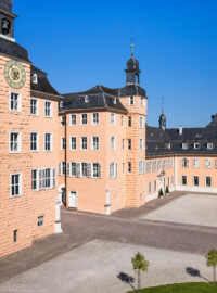 Schloss und Schlossgarten Schwetzingen - Schloss - Mittelbau - Hofseite - Von Südost - Blick vom Dachgeschoss des Südflügels nach Nordwesten auf den Ehrenhof, den Mittelbau, den Südturm (ganz links) und den Nordturm (rechts der Bildmitte), rechts davon der Querbau des Nordflügels mit der Schlosskapelle und ganz rechts der Längsbau des Nordflügels (des Hofkavaliersflügels, heute vom Finanzamt genutzt) (Mittelbau: Länge Westseite ca. 45 Meter, Breite Süd-/Nordseite ca. 38 Meter; Wiederaufbau / Erweiterung: 1698-1717; Architekt: Johann Adam Breunig) (aufgenommen im August 2024, am späten Vormittag)