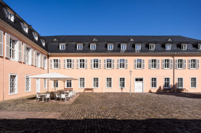 Schloss und Schlossgarten Schwetzingen - Schloss - Südflügel / Hofdamenflügel - Längsbau - Von Süden - Blick von der Nordseite des Küchenflügels auf die Südfassade und das südliche Hauptportal des Längsbaus; links die Ostseite des Querbaus des Küchenflügels (Südflügel: L-förmig, Länge x Breite Längsbau ca. 50 x 14 Meter, Querbau ca. 15 x 11 Meter; Architekt: Johann Adam Breunig (1660-1727); Fertigstellung: 1710, letzte Renovierung: 2009-2012) (aufgenommen im August 2024, um die Mittagszeit)