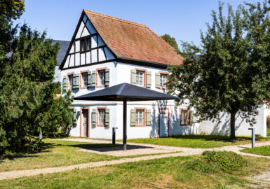 Schloss und Schlossgarten Schwetzingen - Schloss - Hochschule für Rechtspflege & Justizakademie - Studentenhaus - Von Südwest - Blick auf die Westseite (links) und die Südseite (rechts) des Studentenhauses; links im Hintergrund die Südseite des Küchenbaus (Bau: Länge x Breite ca. 10 x 8 Meter; letzte Renovierung: 2009-2012) (aufgenommen im August 2024, am frühen Nachmittag)