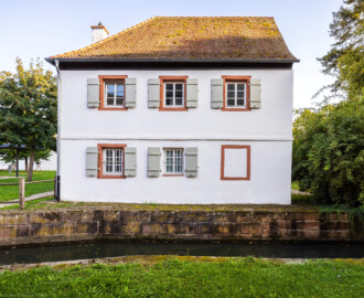 Schloss und Schlossgarten Schwetzingen - Schloss - Hochschule für Rechtspflege & Justizakademie - Studentenhaus - Von Norden - Blick vom Küchenbau auf die Nordseite des Studentenhauses am Abend; vorne der Leimbachkanal (Bau: Länge x Breite ca. 10 x 8 Meter; letzte Renovierung: 2009-2012) (aufgenommen im September 2024, am späten Nachmittag)