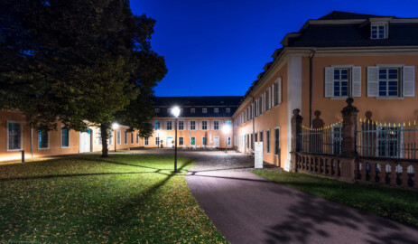 Schloss und Schlossgarten Schwetzingen - Schloss - Hof zwischen Südflügel und Küchenflügel - Von Osten - Blick zur blauen Stunde vom Hofeingang nach Westen in den Hof, auf die Ostfassade des Südflügels (rechts), auf die Ostfassade des Querbaus des Küchenflügels (Mitte) sowie auf die Nordfassade des Längsbaus des Küchenbaus (links); ganz rechts ein Ende des Gitterzauns um den Ehrenhof des Schlosses (Südflügel: L-förmig, Länge x Breite Längsbau ca. 50 x 14 Meter, Querbau ca. 15 x 11 Meter; Architekt: Johann Adam Breunig (1660-1727); Fertigstellung: 1710; Küchenflügel: L-förmig, Länge x Breite Längsbau ca. 75 x 13 Meter, Querbau ca. 25 x 11 Meter; Architekt: Nicolas de Pigage (1723-1796); Fertigstellung: 1761; letzte Renovierung beider Flügel: 2009-2012) (aufgenommen im September 2024, am Abend)